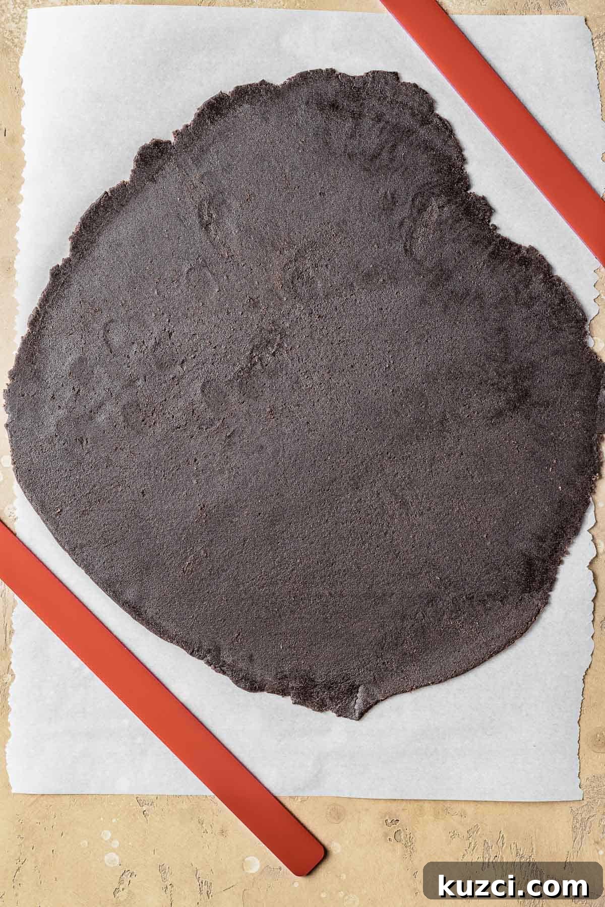 Chocolate tart dough rolled thinly on parchment paper.