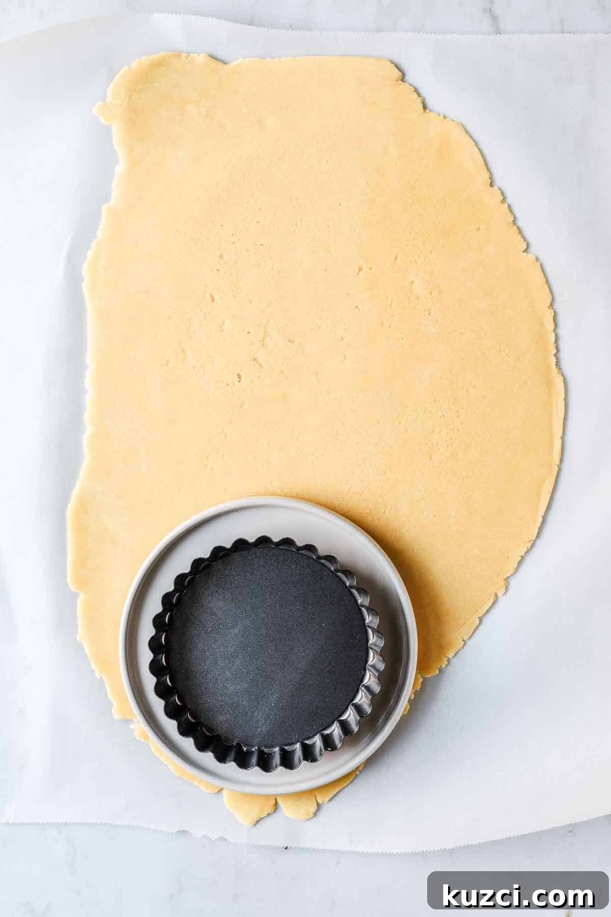 Rolled dough with a plate and small tart pan on top to show size of dough circle needed.