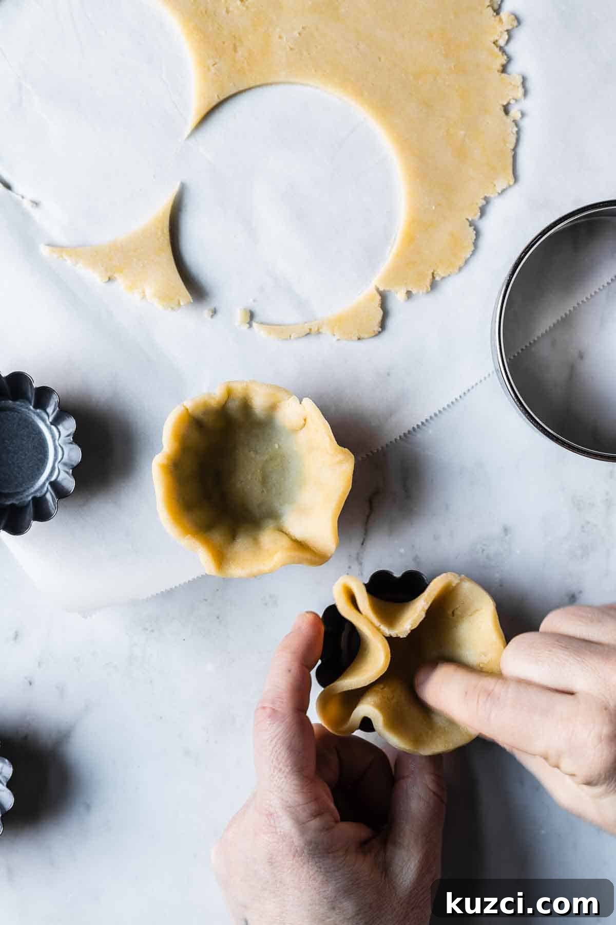 Dough being pressed into small tartlet pans.