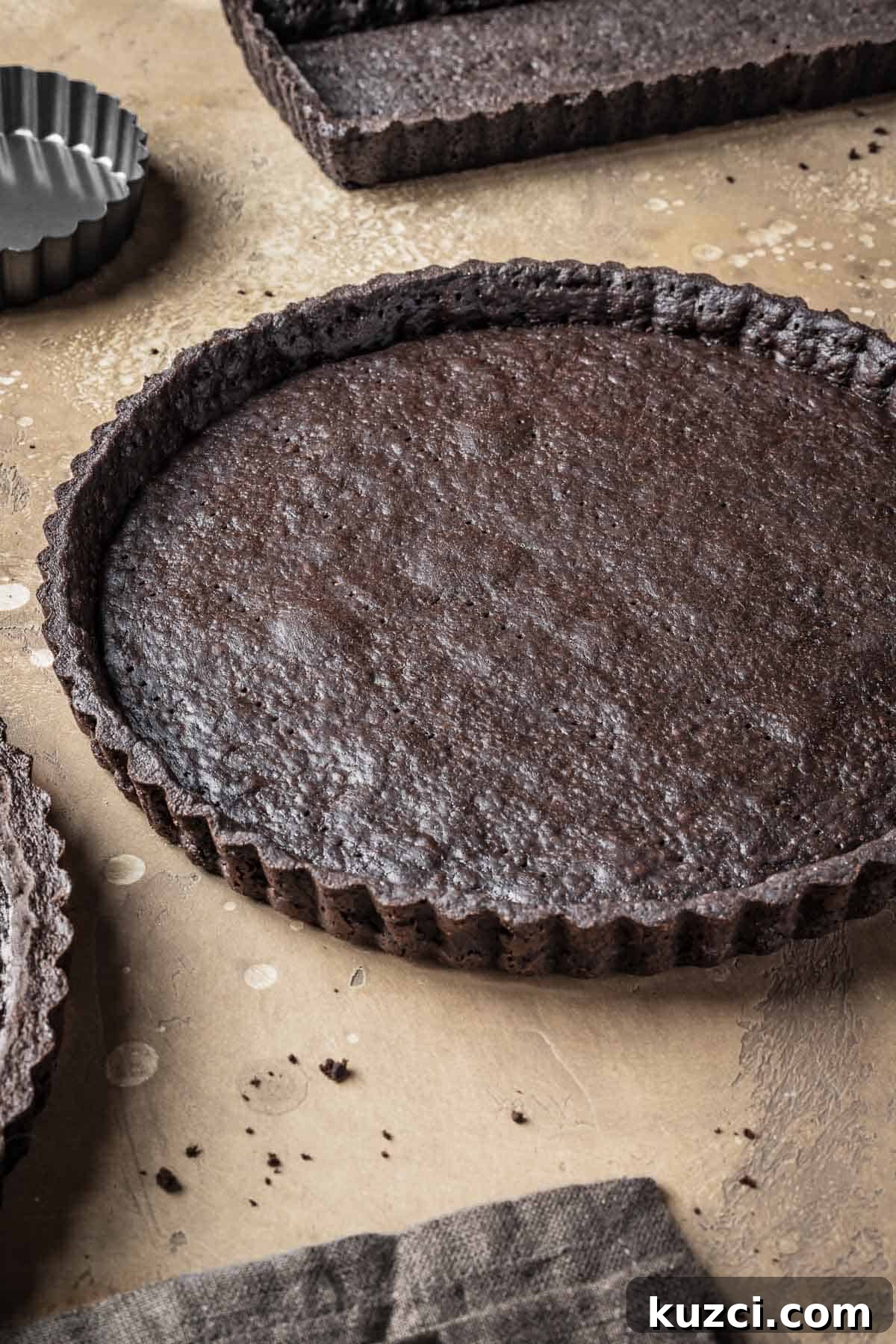 A baked chocolate tart crust with a shiny egg washed interior.