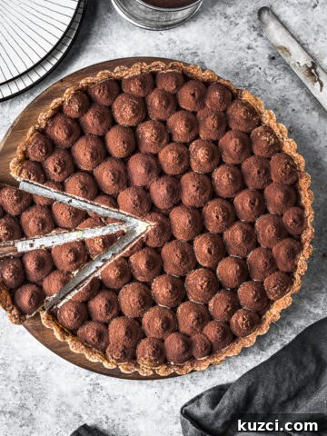 Two slices are cut out of a chocolate tart on a wooden cutting board.