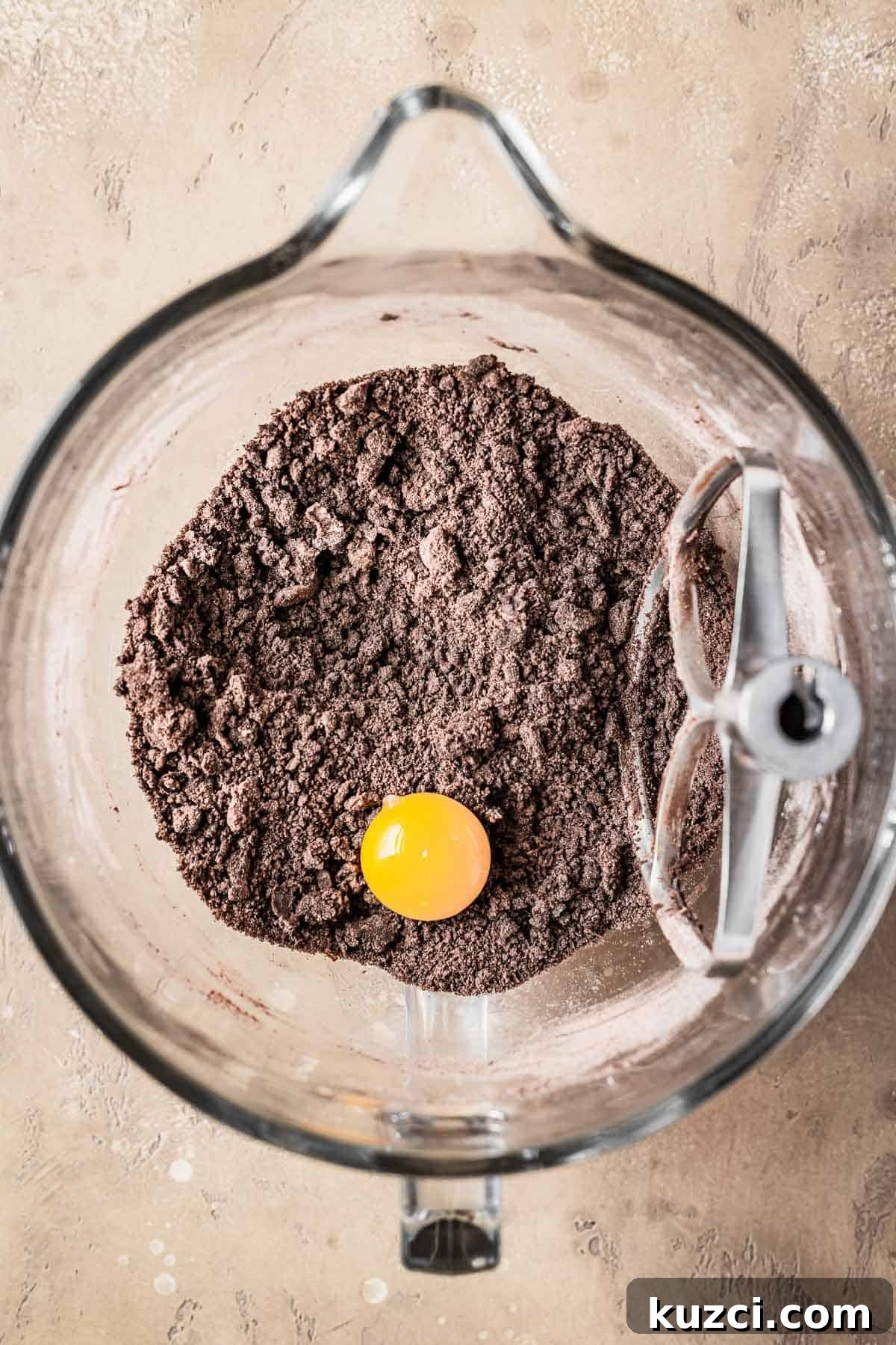 An egg yolk resting on dry ingredients and butter in a mixing bowl.