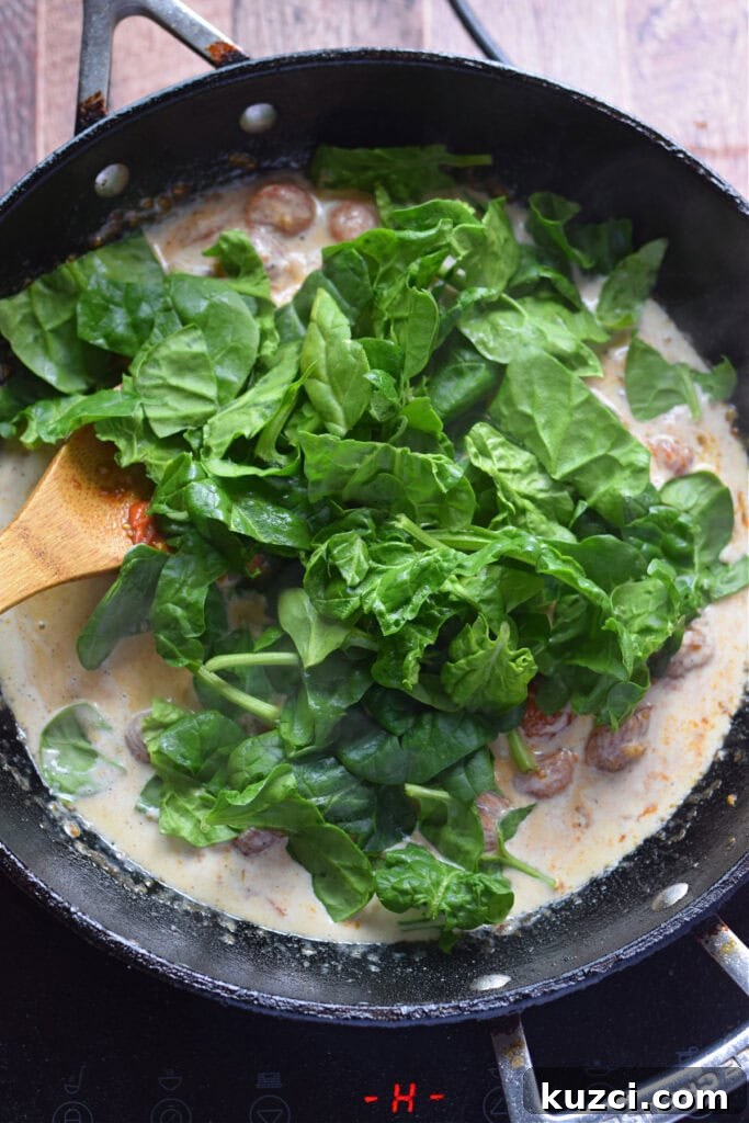 Skillet Chicken with Tomatoes and Spinach Recipe 12 Adding spinach to a skillet with cream and tomatoes.