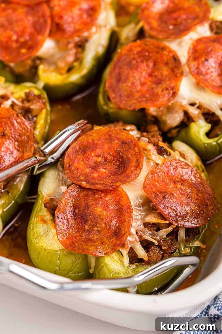 Keto Pepperoni Pizza Stuffed Peppers 2 tongs reaching out for a piece of keto stuffed peppers with pepperoni on top