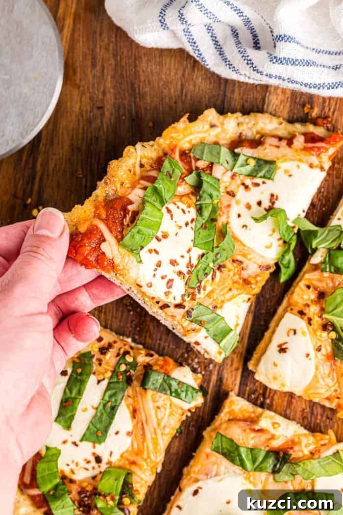 Keto Pepperoni Pizza Stuffed Peppers 15 hand reaching out to grab slice of keto chicken crust pizza off cutting board