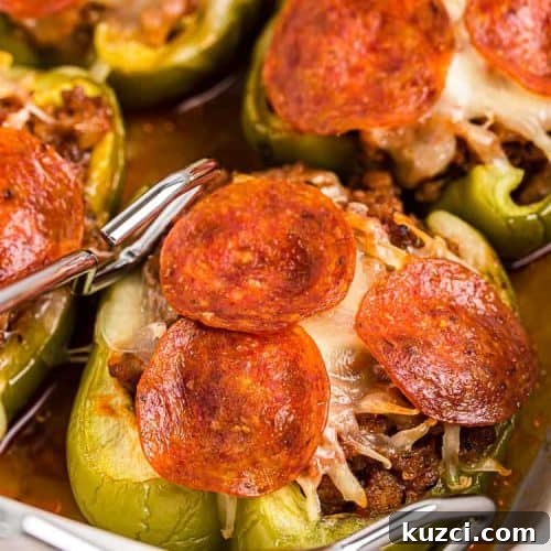 Keto Pepperoni Pizza Stuffed Peppers 17 tongs reaching out for a piece of keto stuffed peppers with pepperoni on top