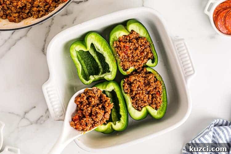 Keto Pepperoni Pizza Stuffed Peppers 4 overhead view of spoon with sausage mixture being spooned into green stuffed bell peppers keto