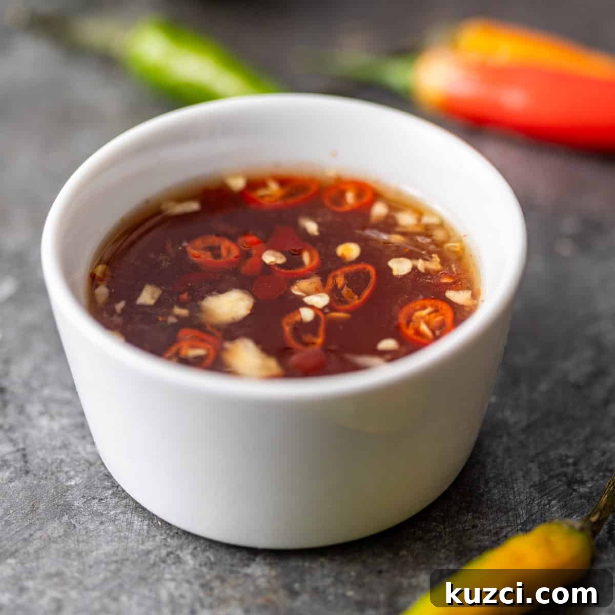 Nuoc Cham Recipe: Authentic Vietnamese Dipping Sauce 2 closeup: nuoc cham in a small white ramekin with peppers showing