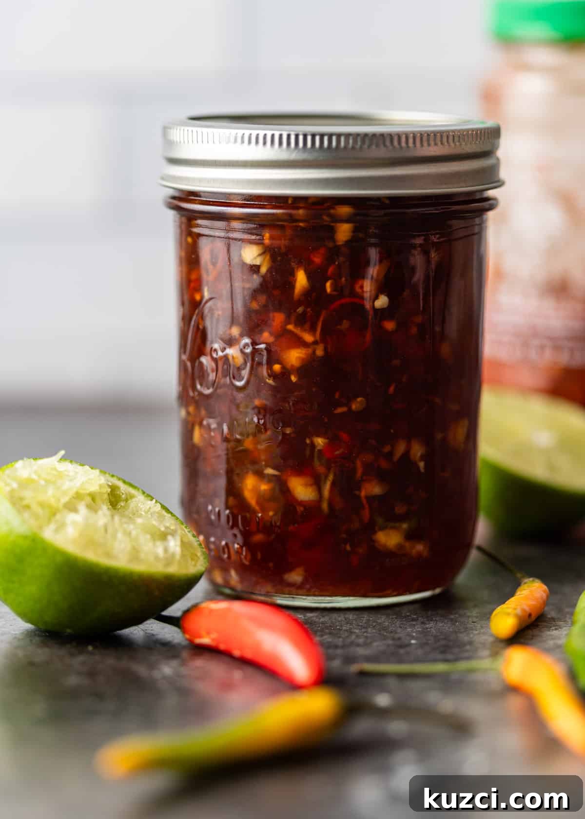 Nuoc Cham Recipe: Authentic Vietnamese Dipping Sauce 8 a mason jar full of vietnamese dipping sauce with lime and peppers to the side