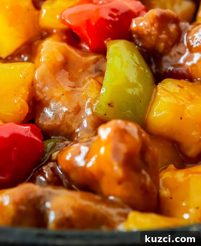 Crispy Sweet and Sour Chicken Recipe That Beats Takeout 6 A plate of sweet and sour chicken with bell peppers, onions, pineapples tossed in a sweet and savory sauce over rice.