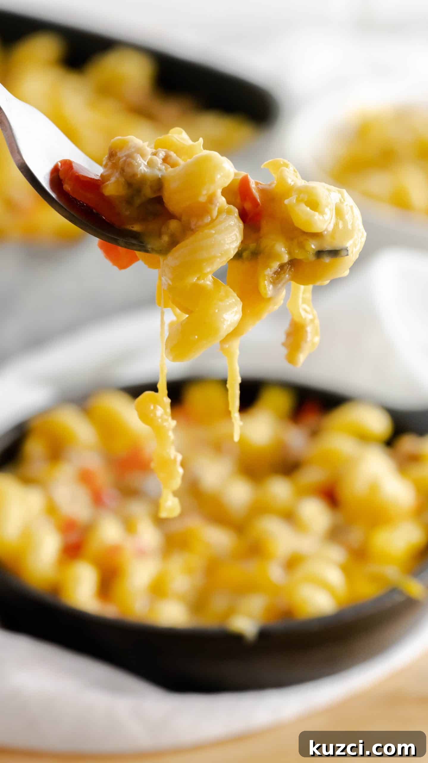 Sausage and Peppers Mac and Cheese Recipe 4 A forkful of sausage mac and cheese with red peppers.