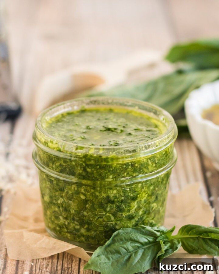 Nut free Basil Pesto in a jar with basil leaves around it.