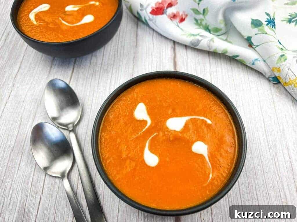 Two bowls of oven-roasted tomato soup with cream swirls.