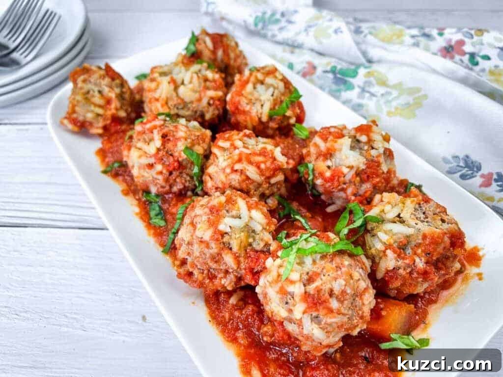 A white rectangular plate with slow cooker porcupine meatballs, garnished with fresh herbs.