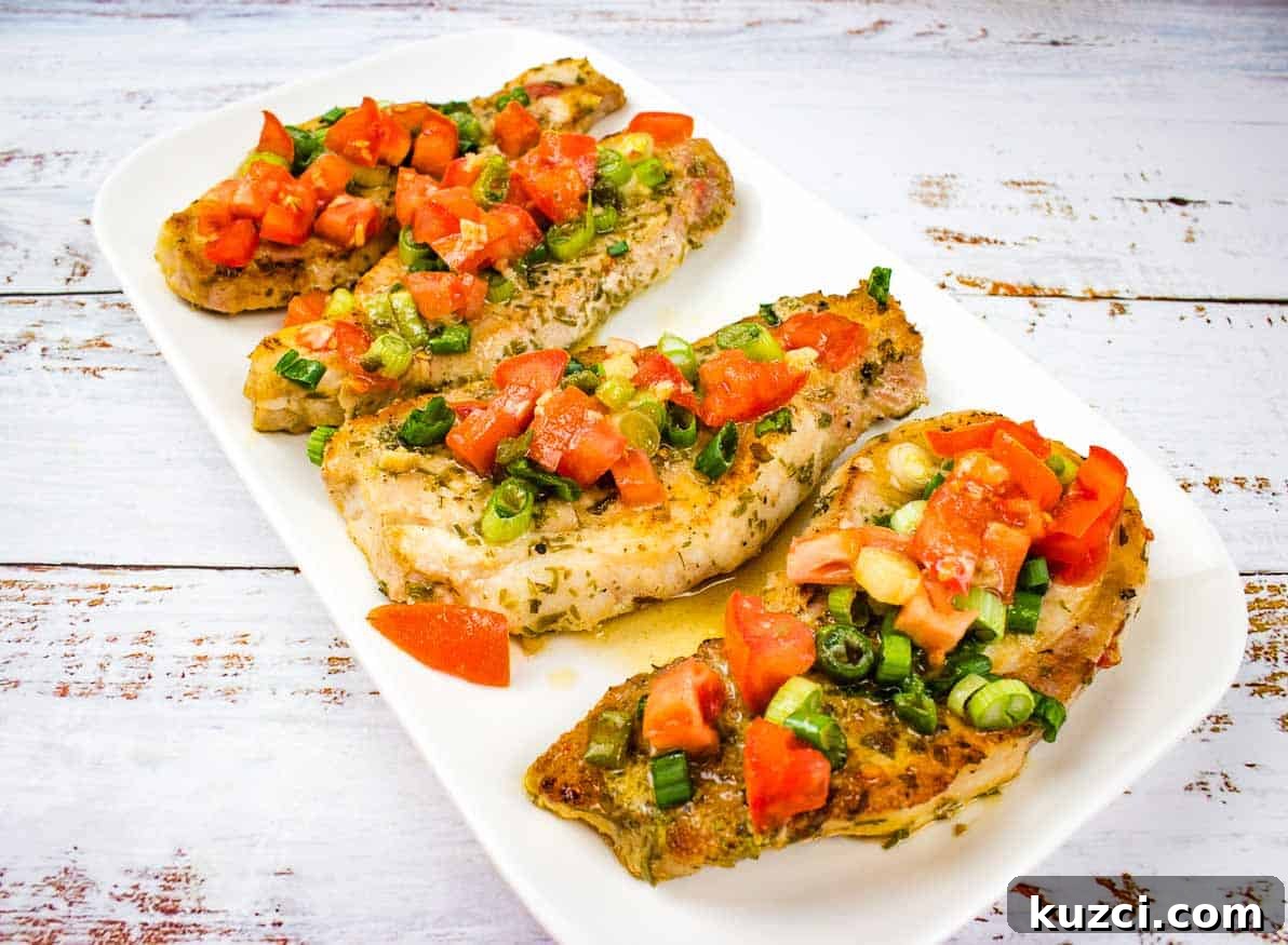 Three pork chops with tomato and green onion on a white plate.