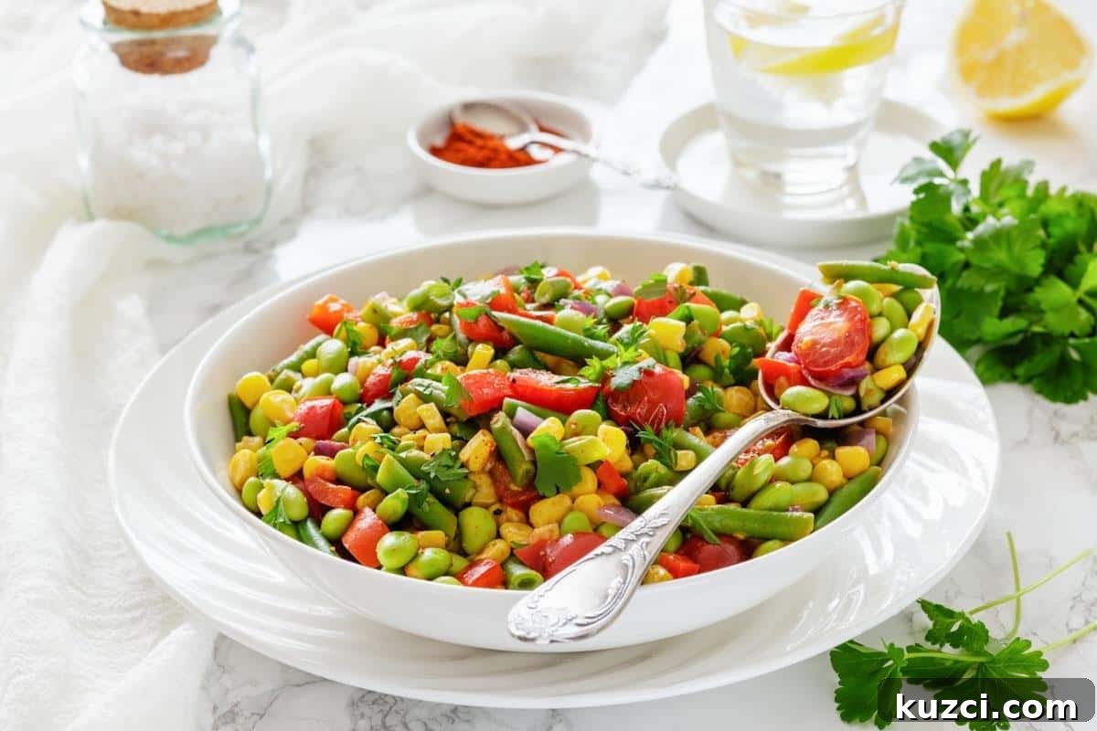 A white bowl filled with Southern Succotash with a serving spoon resting on the side.