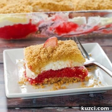 Rhubarb dessert on a white plate with fork on the right side and pan of more dessert in the background