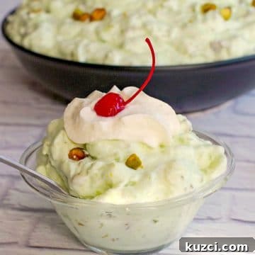 pistachio fluff in a glass bowl with a larger bowl in the background