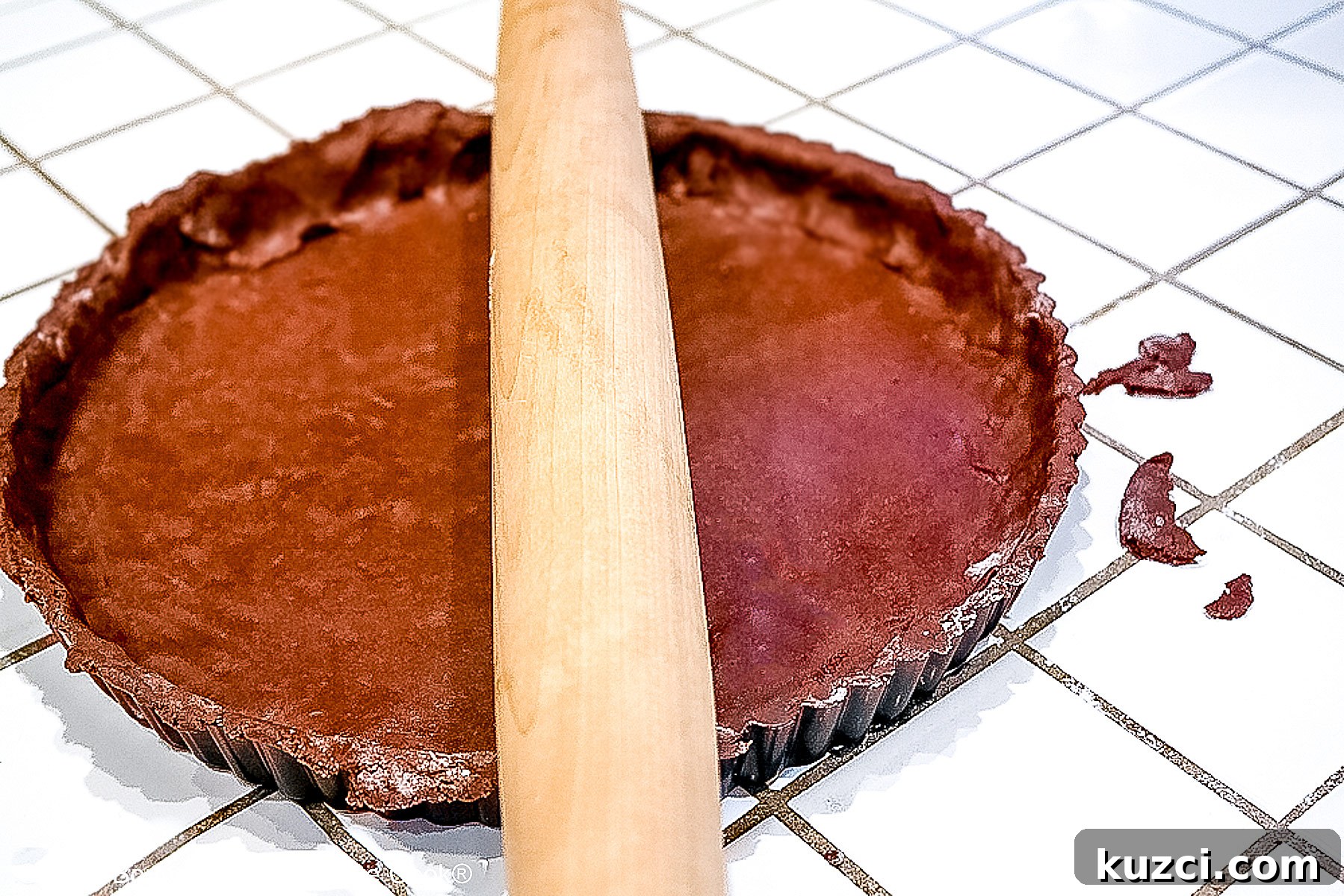 Cutting off the excess dough by rolling the pin over the edges; right side is done, left side is undone. 