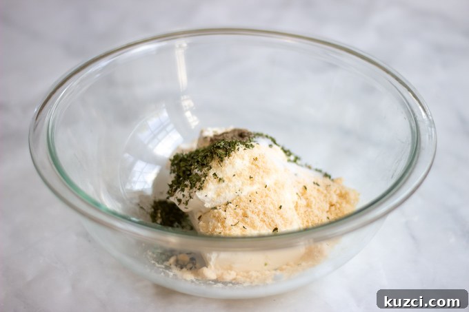 a bowl with cream cheese,sour cream, parmesan cheese and parsley. 