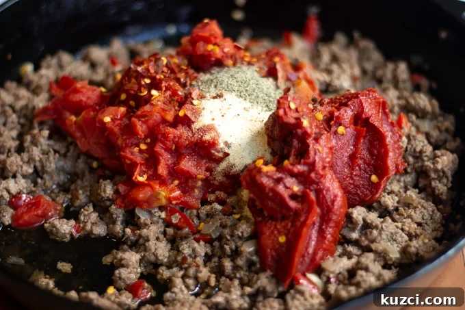 Meat sauce ingredient going into the skillet with the ground beef