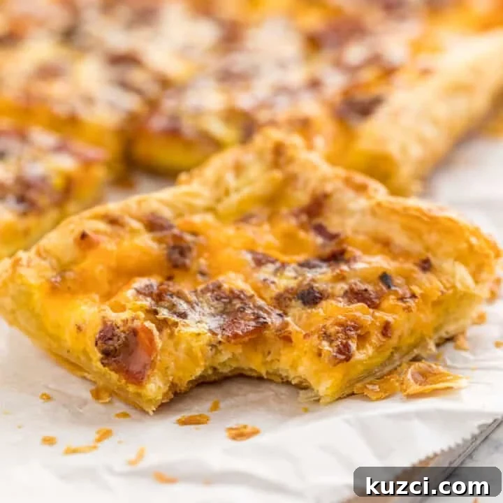 A slice of breakfast pizza on parchment and a cutting board with a bite taken out of it and the rest of the pizza in the background.