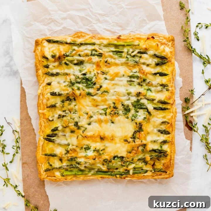 An overhead image of the asparagus puff pastry tart on a parchment lined cutting board with sprigs of thyme around it.