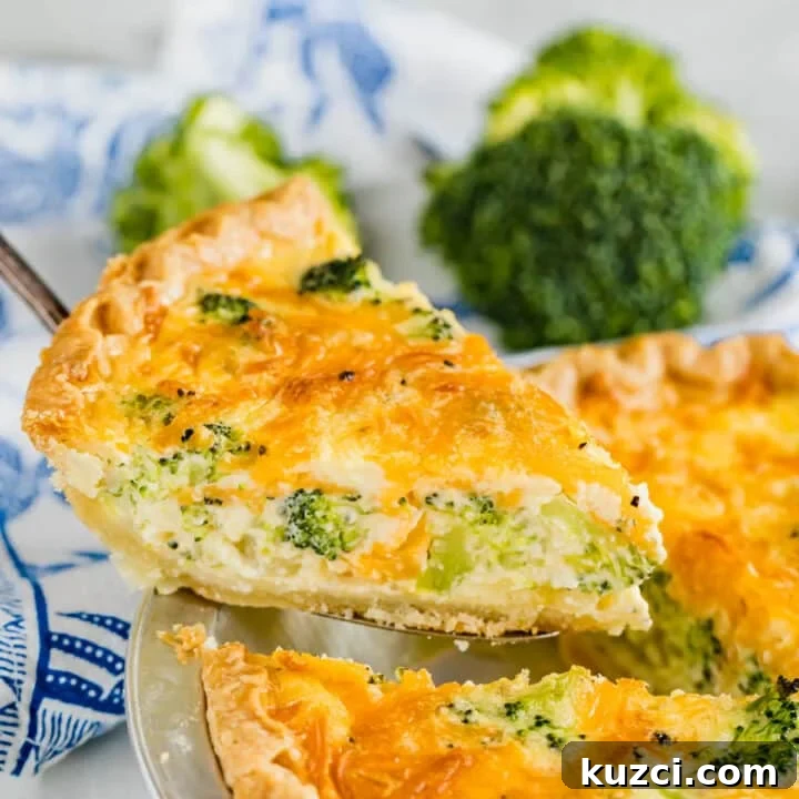 A slice of quiche been pulled up and out of a broccoli quiche with broccoli and a cloth napkin in the background.