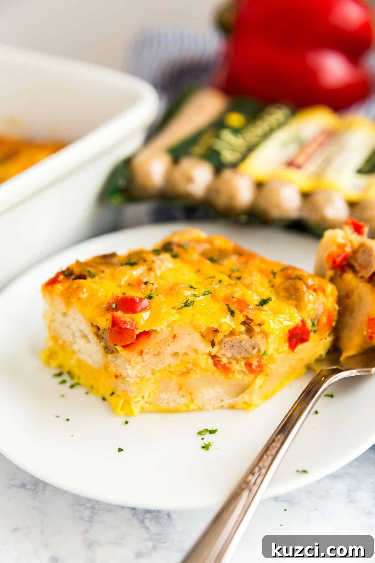 A piece of breakfast casserole on a white plate with a bite taken from it and the fork next to it.