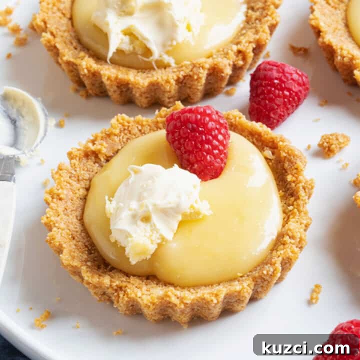 A lemon curd tartlet topped with raspberries and cream.
