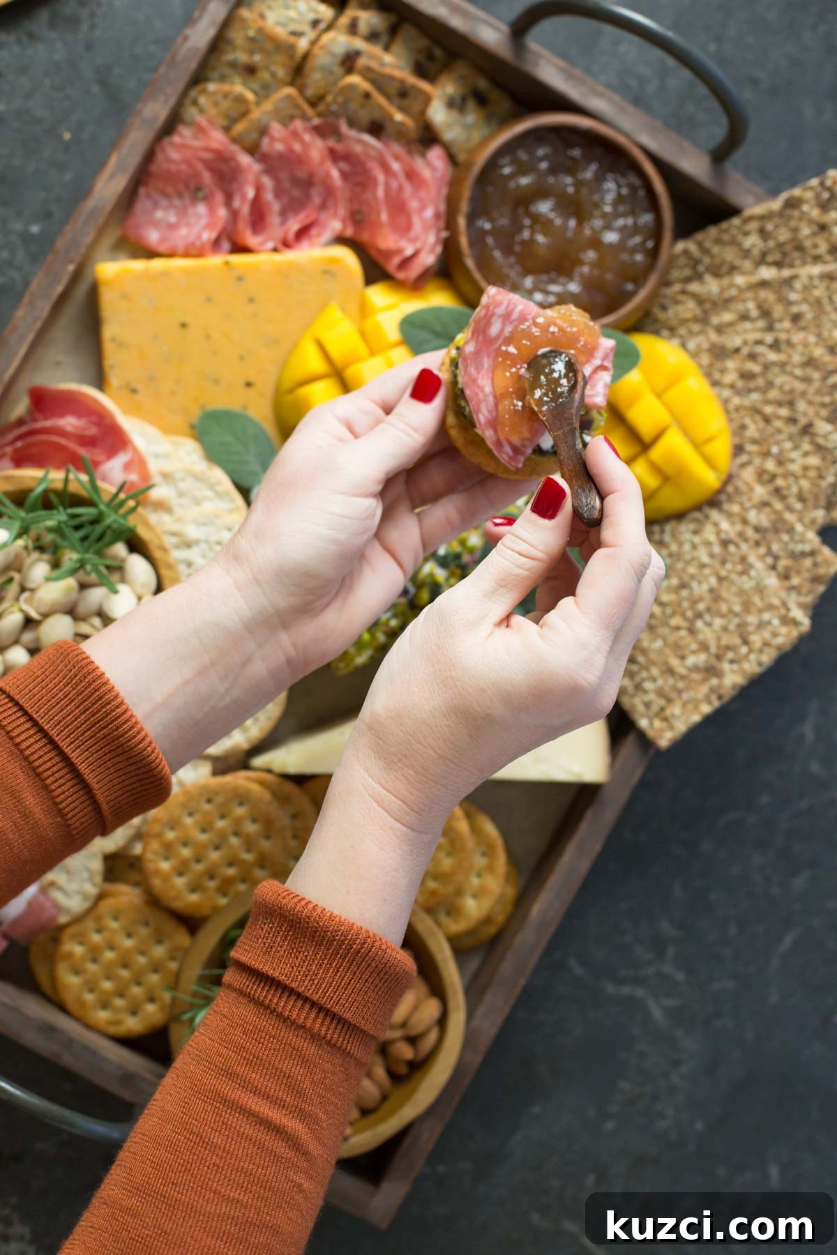 Mango Cheese Log with Pistachio Crust 5 Hands in shot above view of charcuterie.