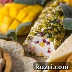 Close up view of Pistachio Crusted Cheese Log displayed as part of a charcuterie.