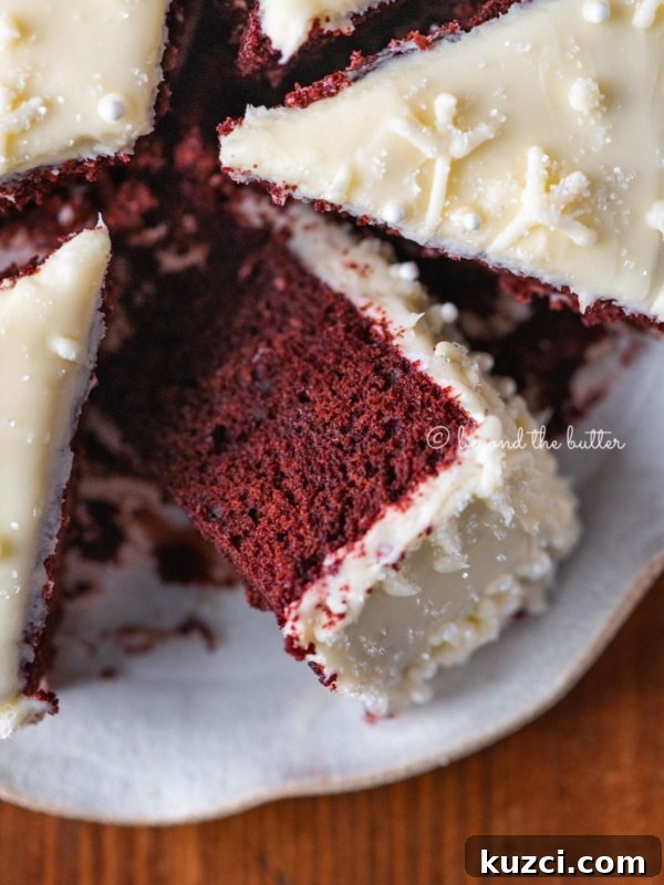 Moist Single Layer Coconut Cake Recipe 9 Sliced red velvet cake with cream cheese frosting on a scalloped edge dessert plate with red plaid background.
