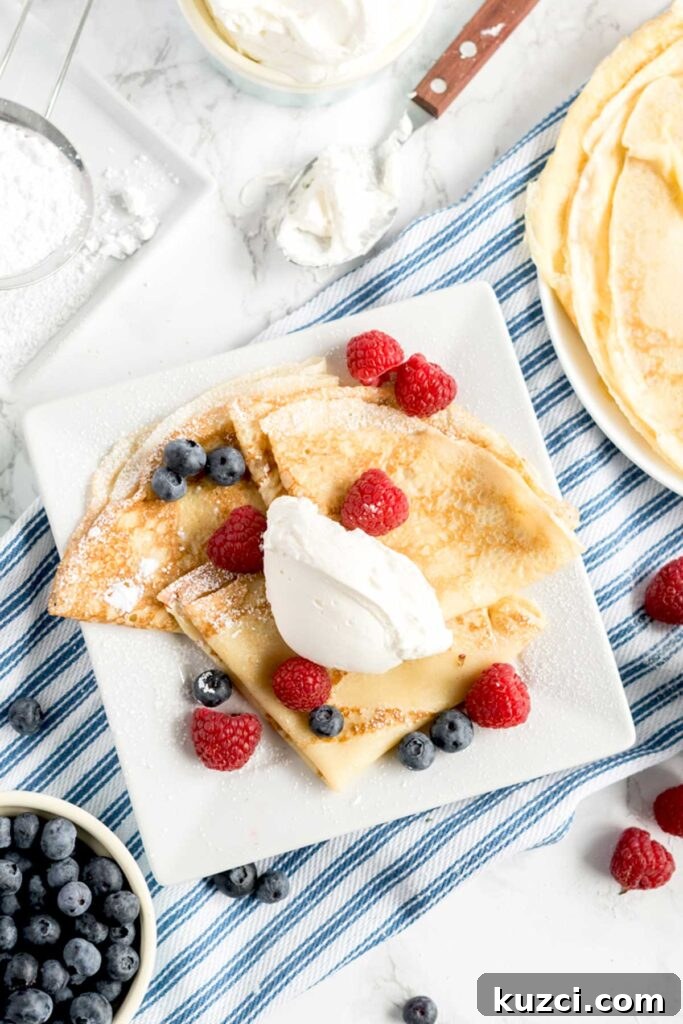 Top view of French Crepes served with sweet whipped cream and fresh berries.