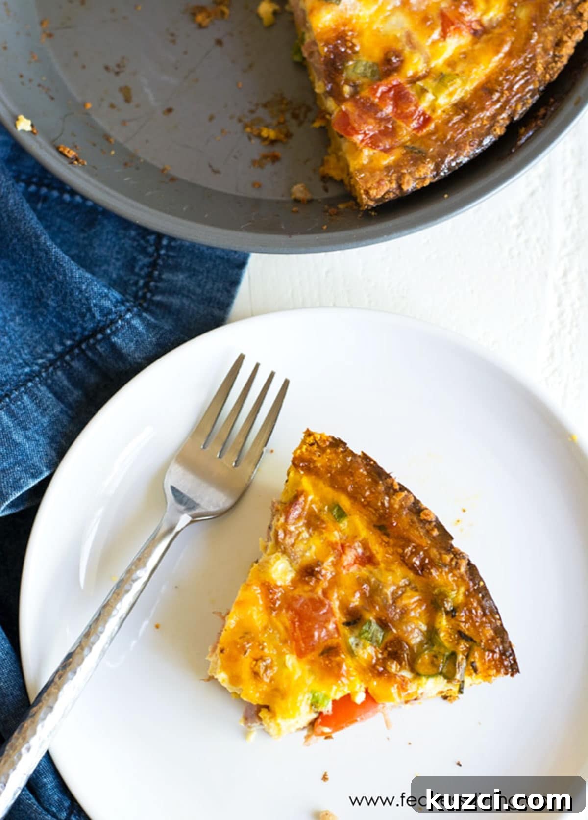 Gluten-Free Cheddar and Broccoli Quiche 6 The top view of a slice of quiche on a plate next to the whole quiche.