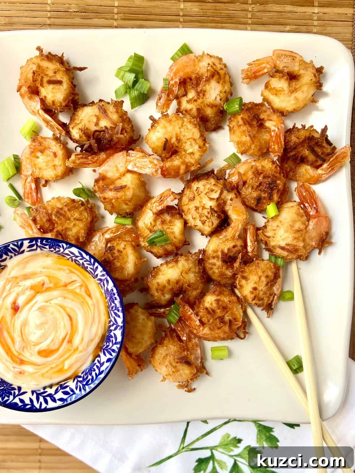 Coconut fried shrimp on white platter with dipping sauce.