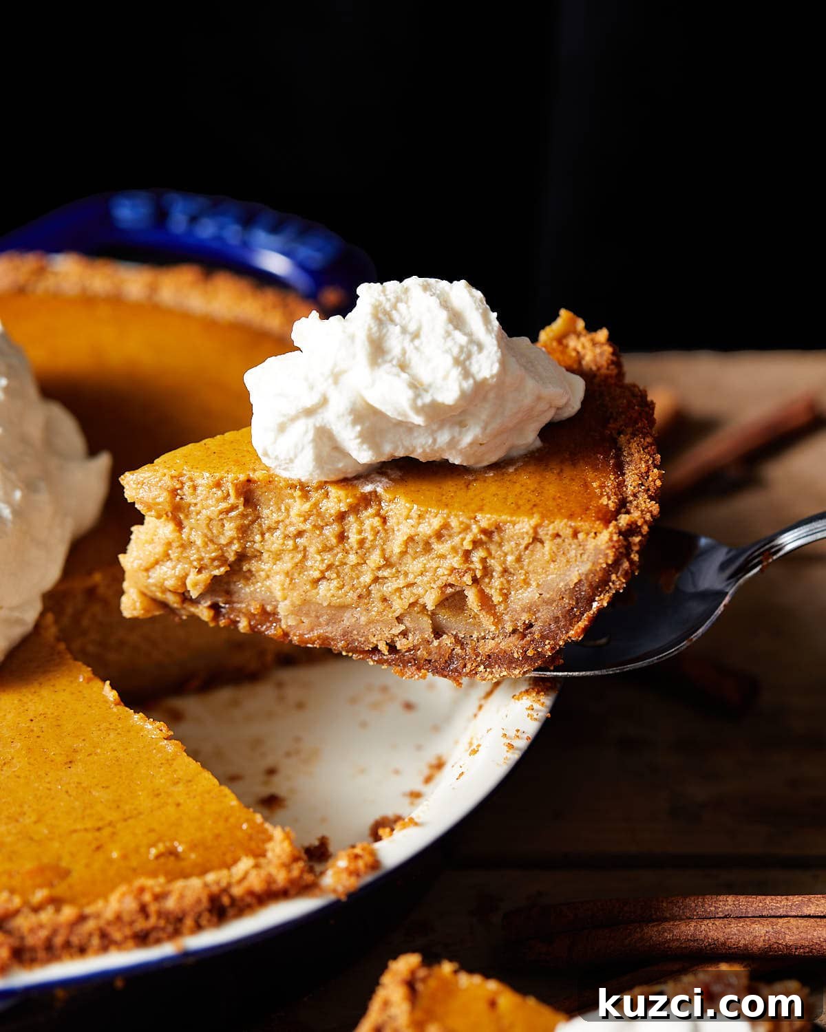 Pumpkin Pie with Graham Cracker Crust Recipe 6 A slice of pie being removed from the dish with whipped cream.