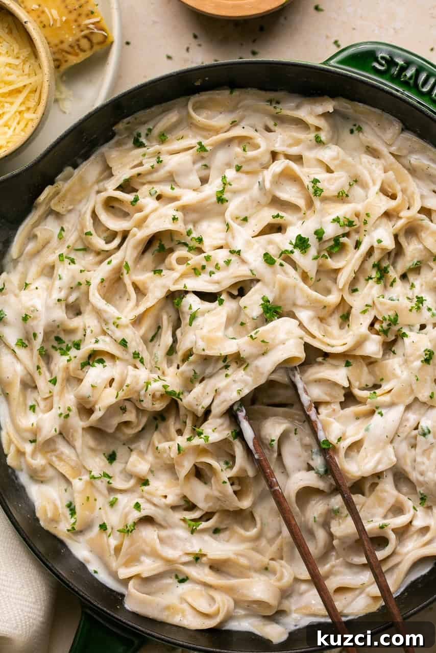 10-Minute High-Protein Cottage Cheese Alfredo Sauce 5 pasta with alfredo sauce in a cast iron skillet with tongs
