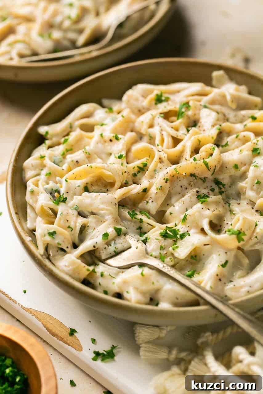10-Minute High-Protein Cottage Cheese Alfredo Sauce 6 a bowl of pasta with alfredo sauce topped with parsley with a fork in it