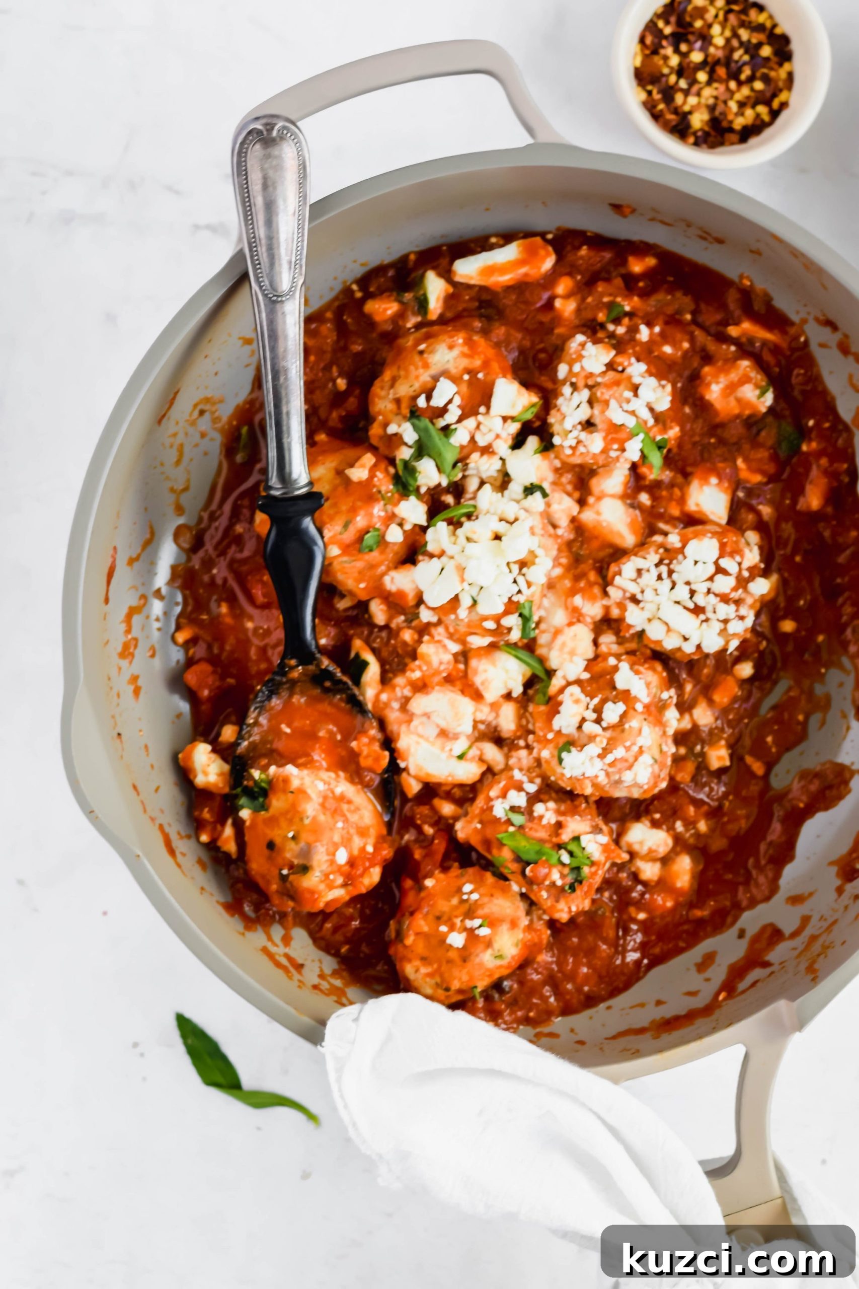 Simple Ground Turkey Recipes That Taste Delicious 11 Zesty Turkey Feta Meatballs in a gray skillet with a serving spoon.