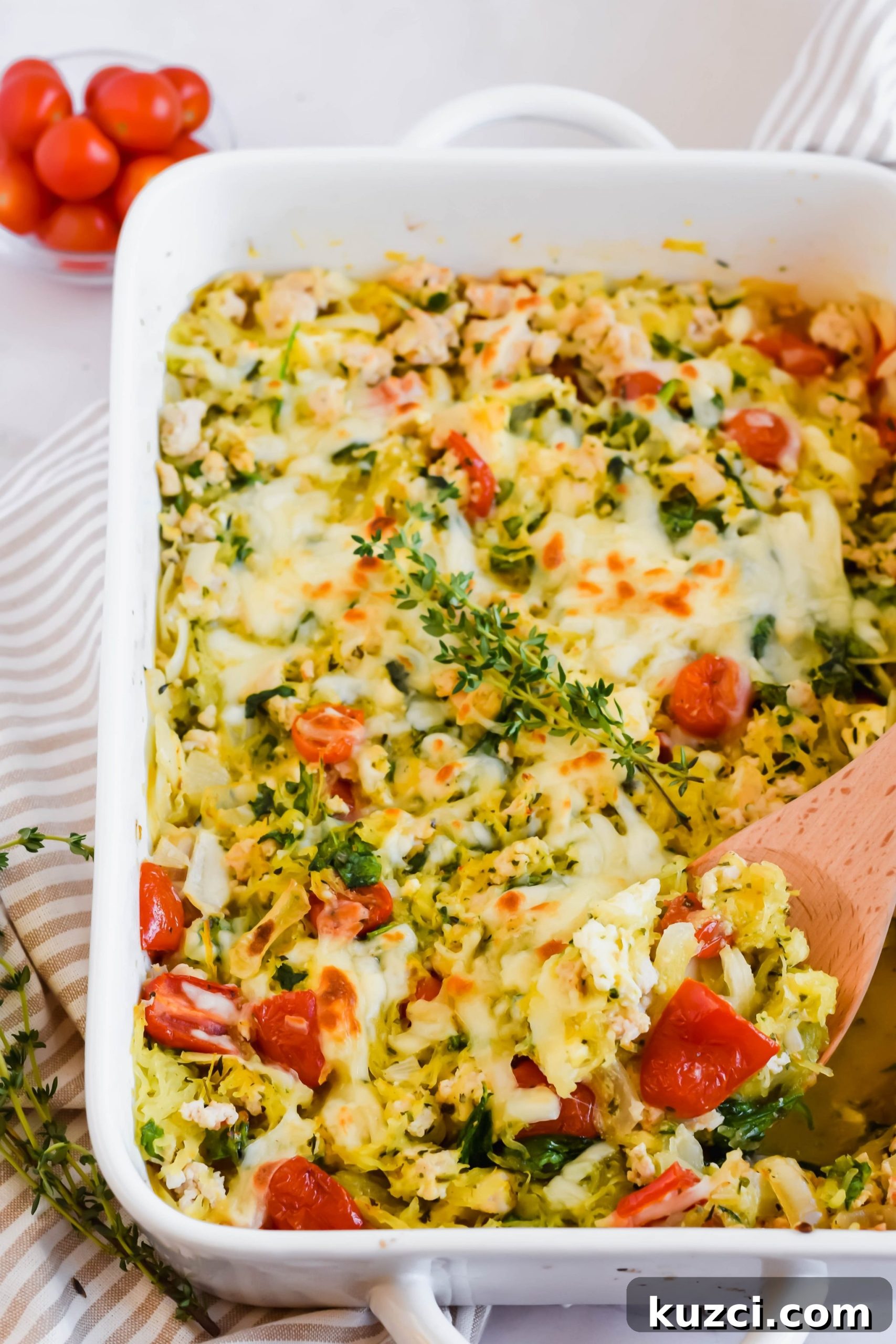 Simple Ground Turkey Recipes That Taste Delicious 15 Large white baking dish with spaghetti squash feta cheese casserole recipe with wooden spoon topped with fresh thyme sprig in dish.