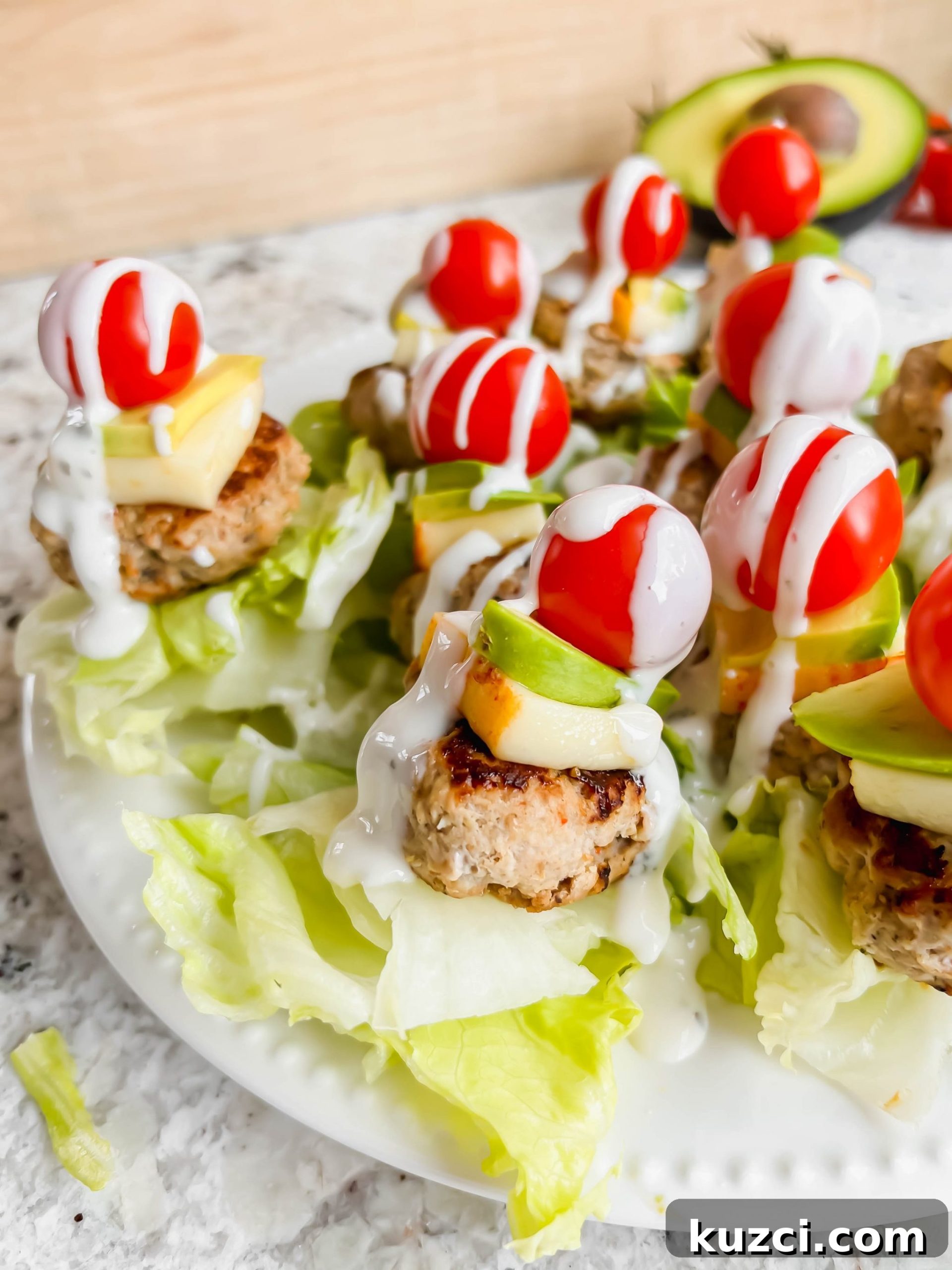 Simple Ground Turkey Recipes That Taste Delicious 19 mini turkey burger on a stick topped with cheese and avocado on a white plate.