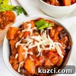 Simple Ground Turkey Recipes That Taste Delicious 22 chunky sweet potato turkey chili in white bowl topped with cheese.