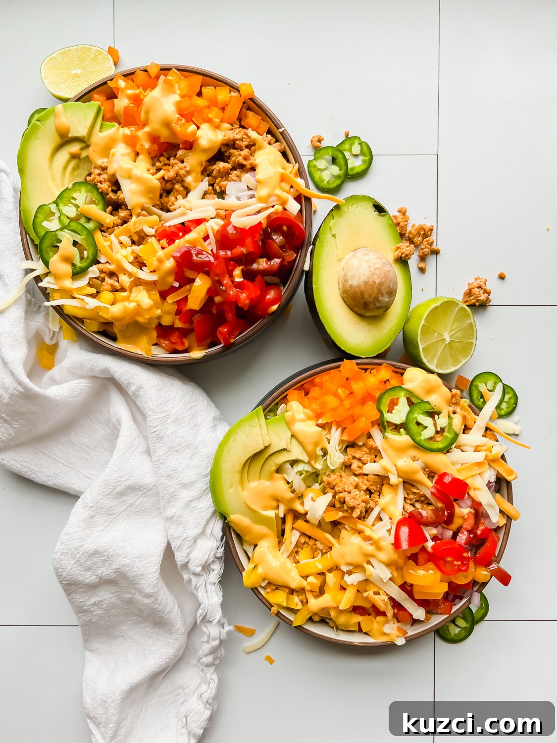 Simple Ground Turkey Recipes That Taste Delicious 7 two bowls loaded with taco salad on a white tiled background.