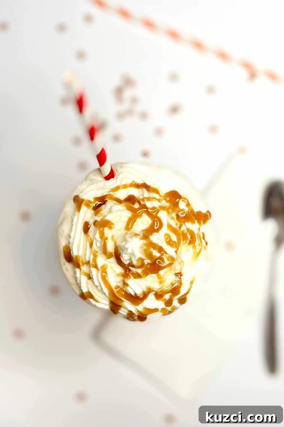 Creamy Butterscotch Milkshake Recipe 5 Top of milkshake, with caramel sauce drizzled on top and a red and white striped straw.