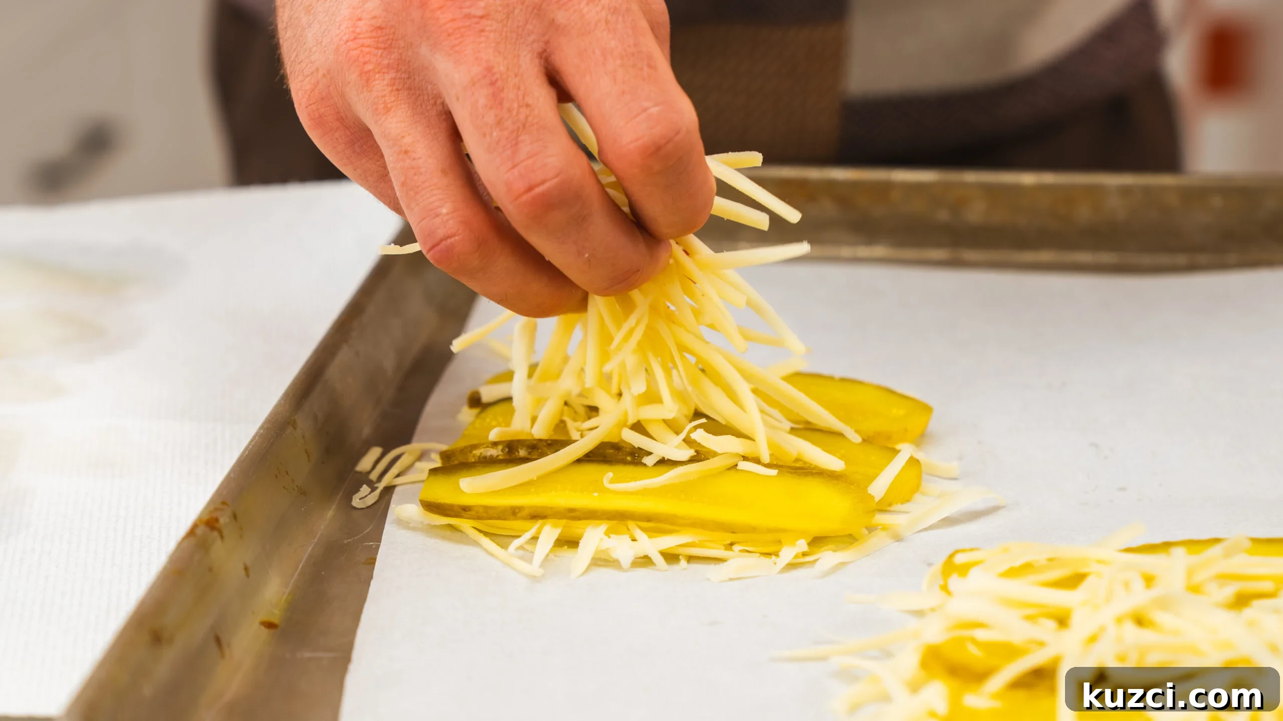 Viral Pickle Sandwich Recipe: Low-Carb, Loaded with Crunch 3 Shredded old white cheddar being added to sliced pickles on a baking sheet.