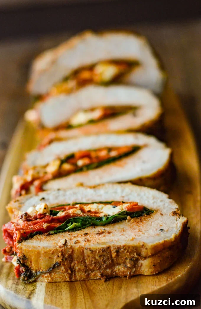Stuffed Pork Roast with Roasted Red Peppers Feta and Spinach 7 Pork roast stuffed with roasted red peppers, feta, and spinach, sliced and sitting on a wooden board.