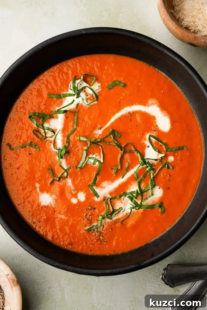 overhead shot of tomato bisque soup with basil, cream, and pepper