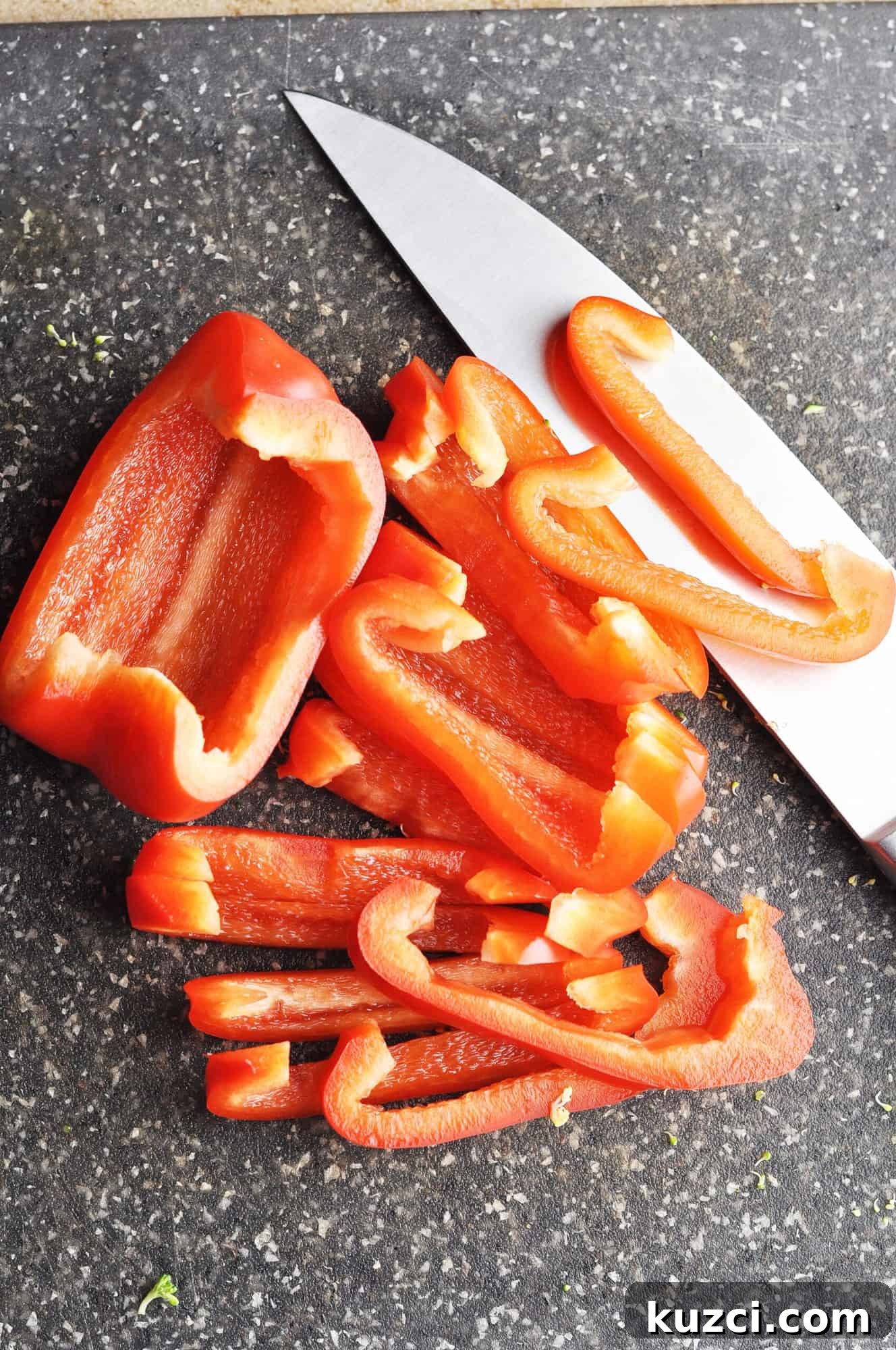Sliced red bell pepper on cutting board with knife.