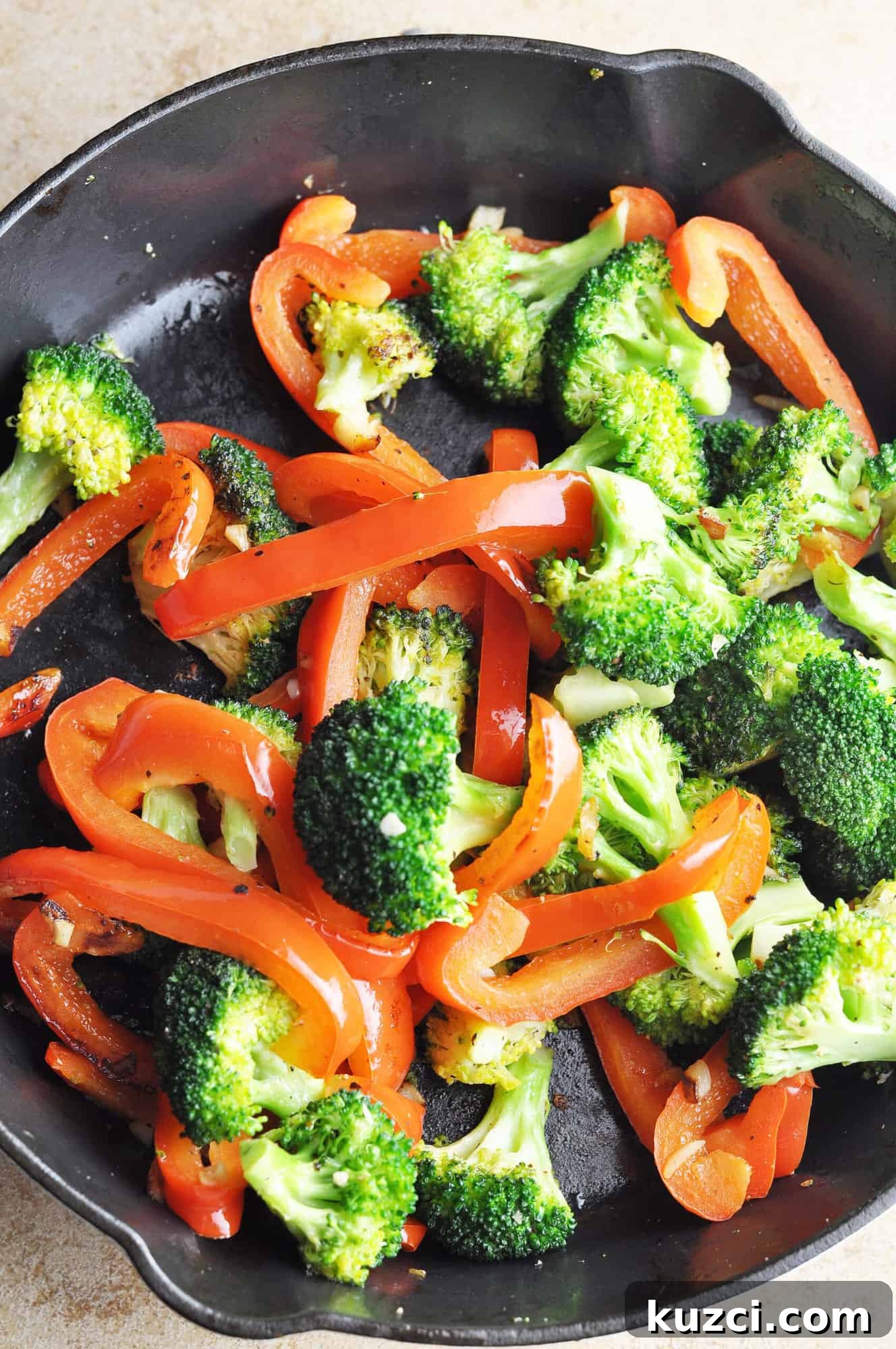 Cooked broccoli with red peppers and garlic in cast iron skillet.